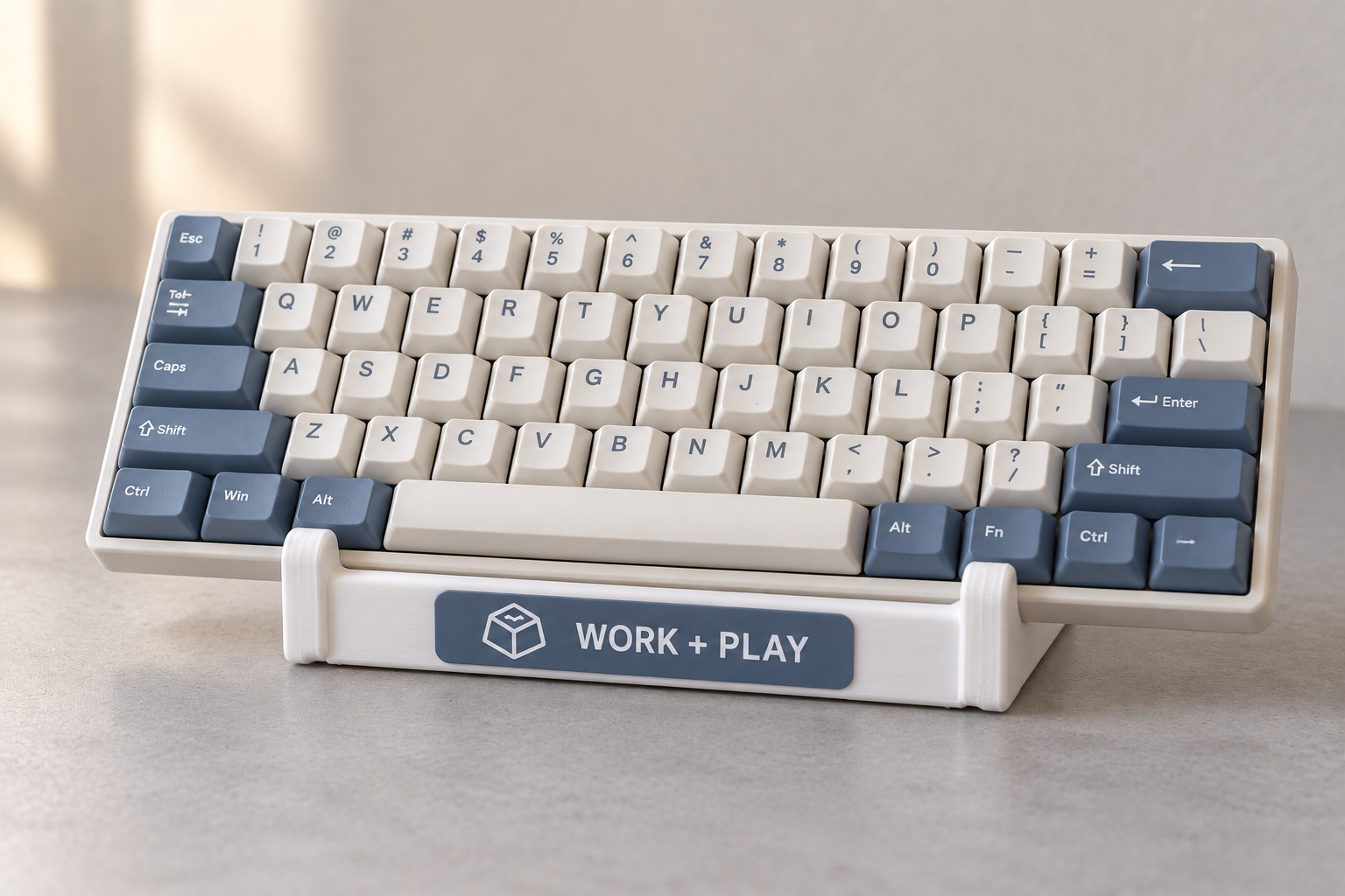 ภาพจำลองคีย์บอร์ดสีงาช้างและน้ำเงิน วางบนขาตั้งสีขาวพร้อมป้าย WORK + PLAY สีน้ำเงิน